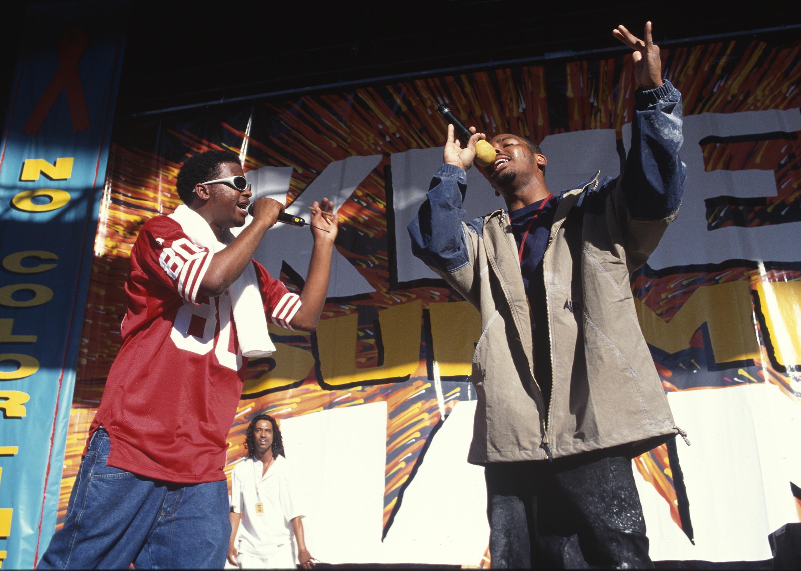 Yukmouth and Numskull of Luniz perform on an outdoor stage.