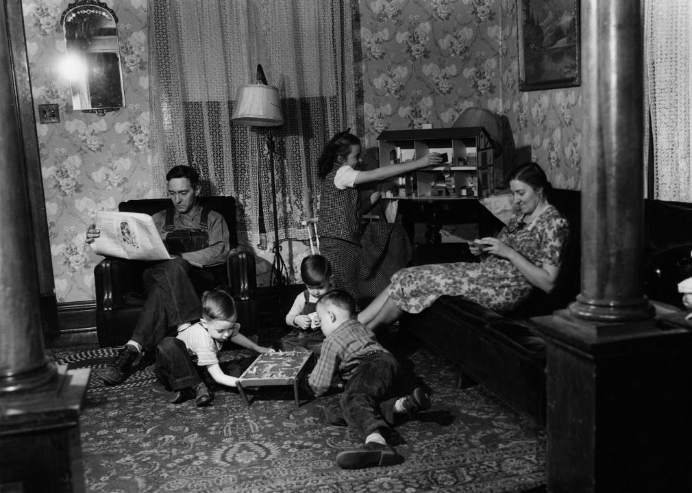 A worker relaxes with a newspaper at home with wife and four children