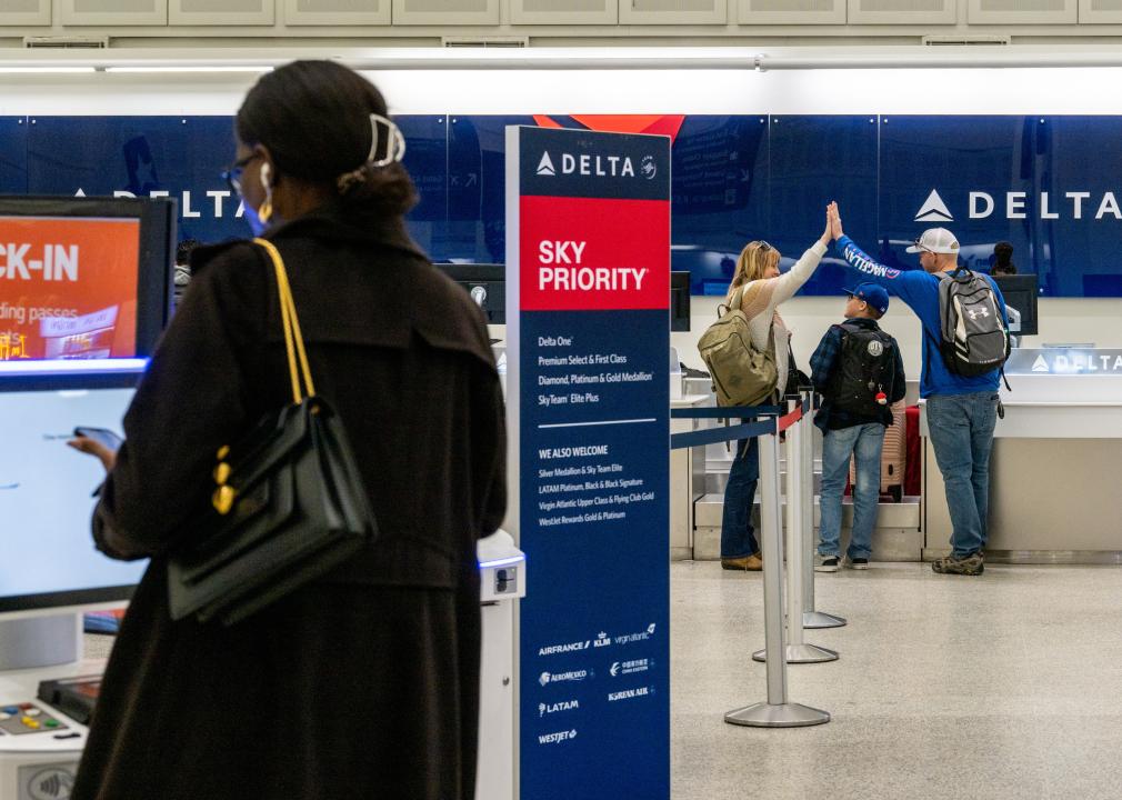 A woman checks in for her flight as a family celebrates at a Delta Airlines check-in counter.
