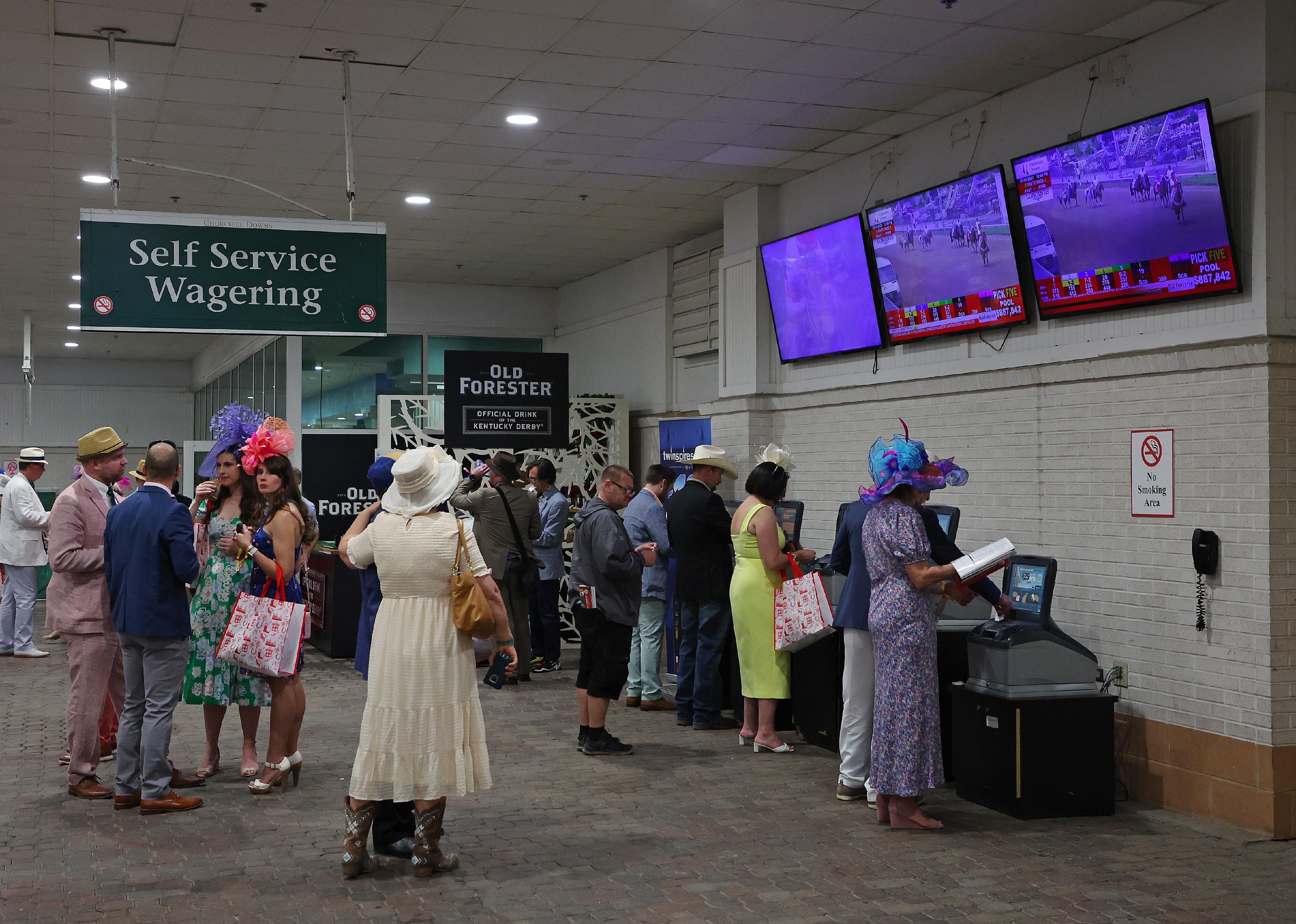 Spectators wait in line to wager on races prior to the 149th running of the Kentucky Derby.