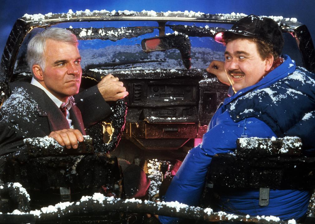 Steve Martin and John Candy sit in a destroyed car in a scene from the film 'Planes, Trains & Automobiles' from 1987.