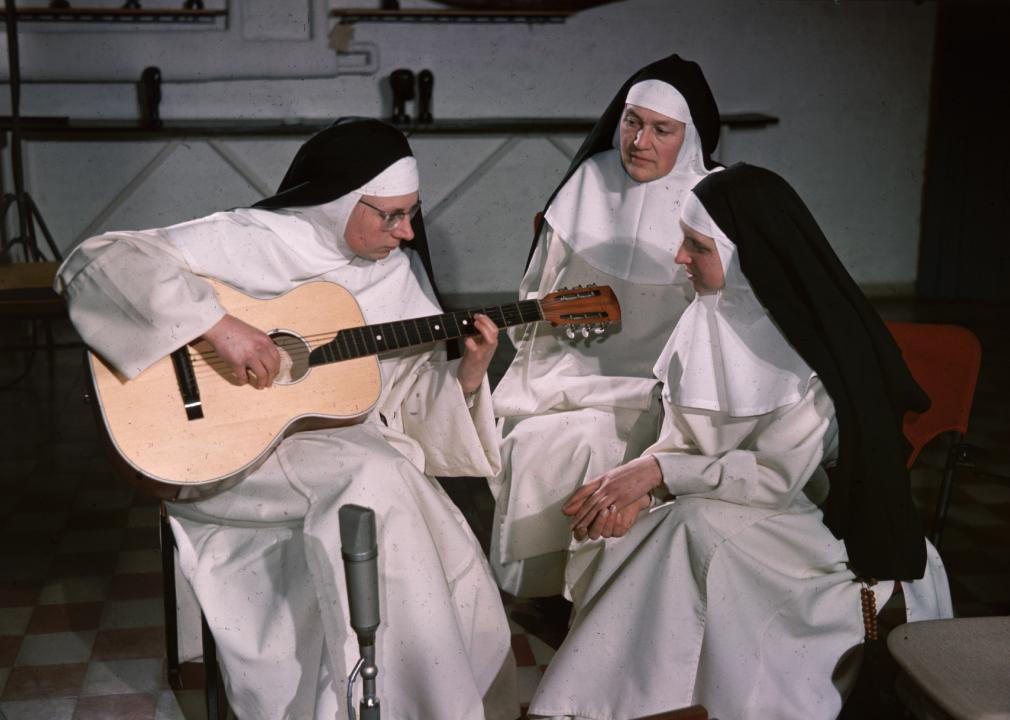 The singing nun performs on her guitar for two other nuns.