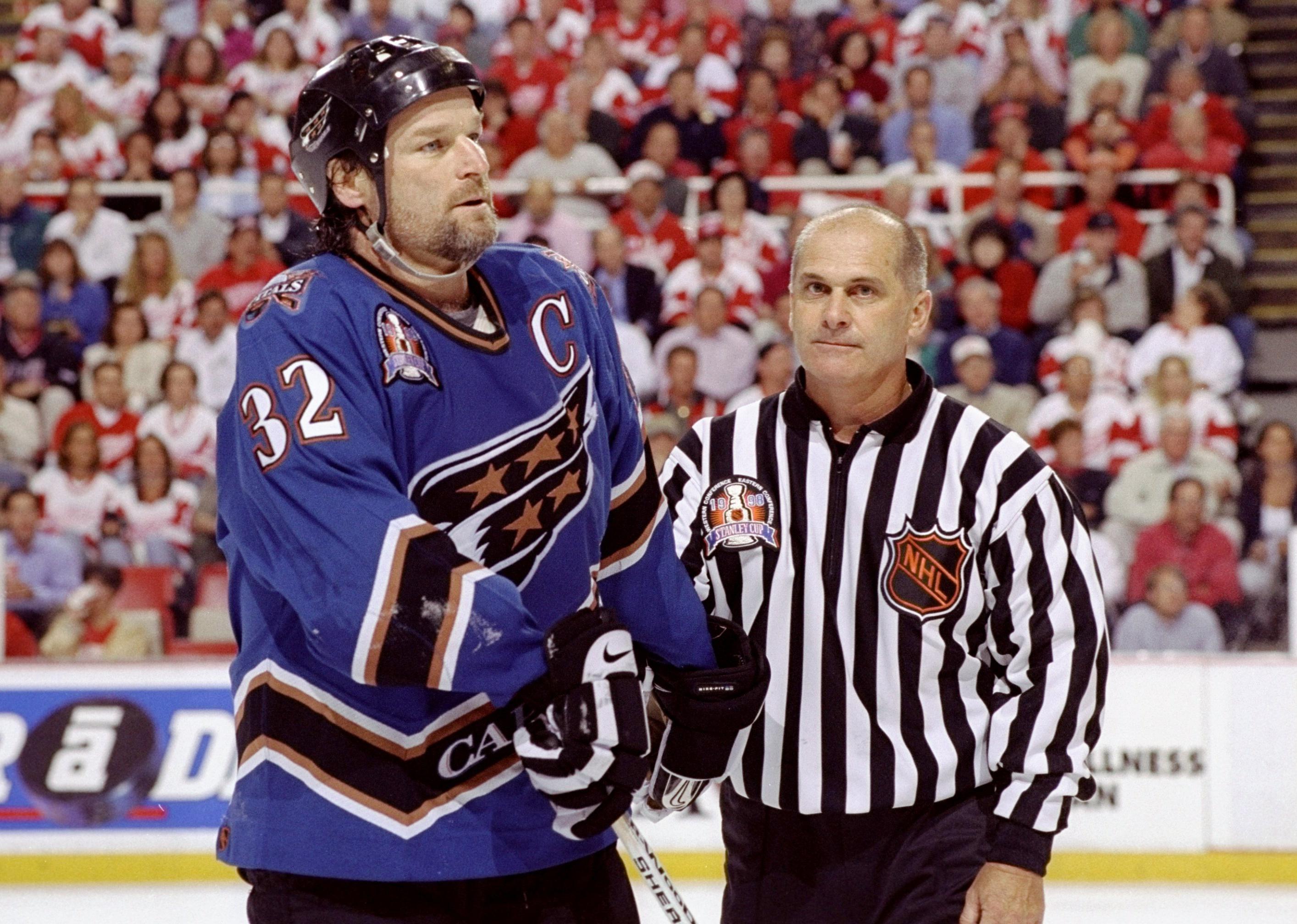 Dale Hunter is escorted off by a referee during the Stanley Cup Finals.