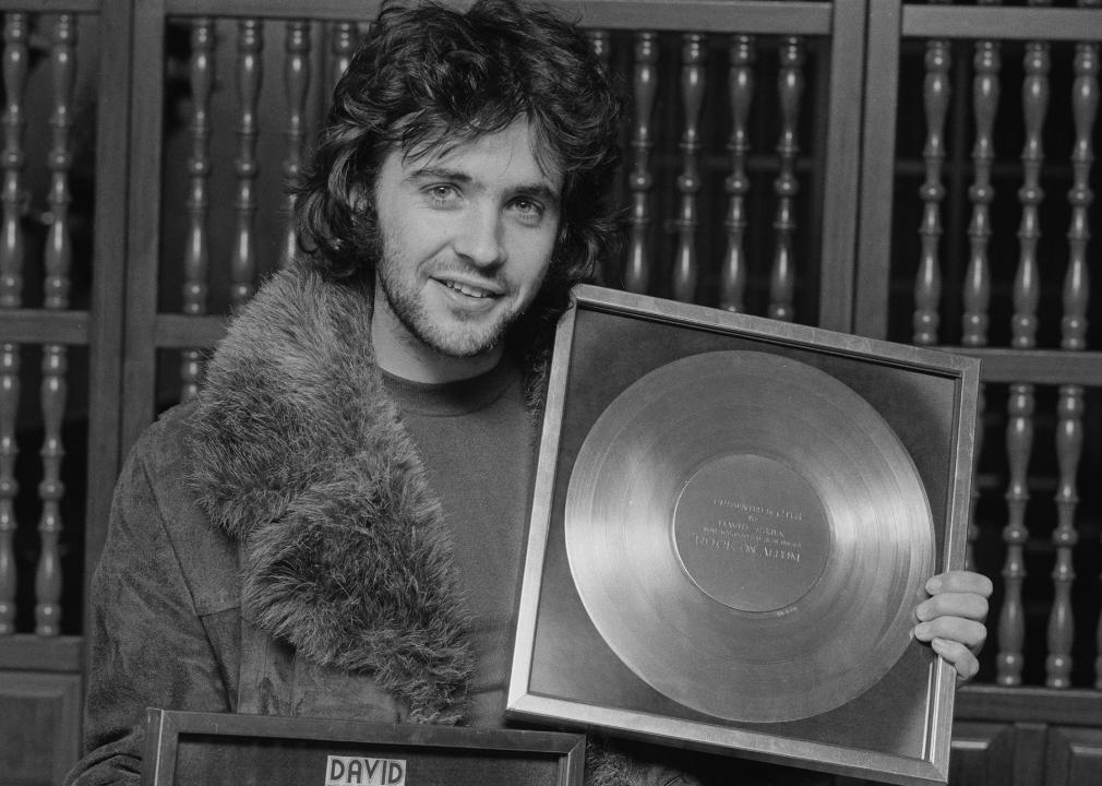 David Essex holding a gold record awarded to him for 100,000 sales of his album 'Rock On', 1974.