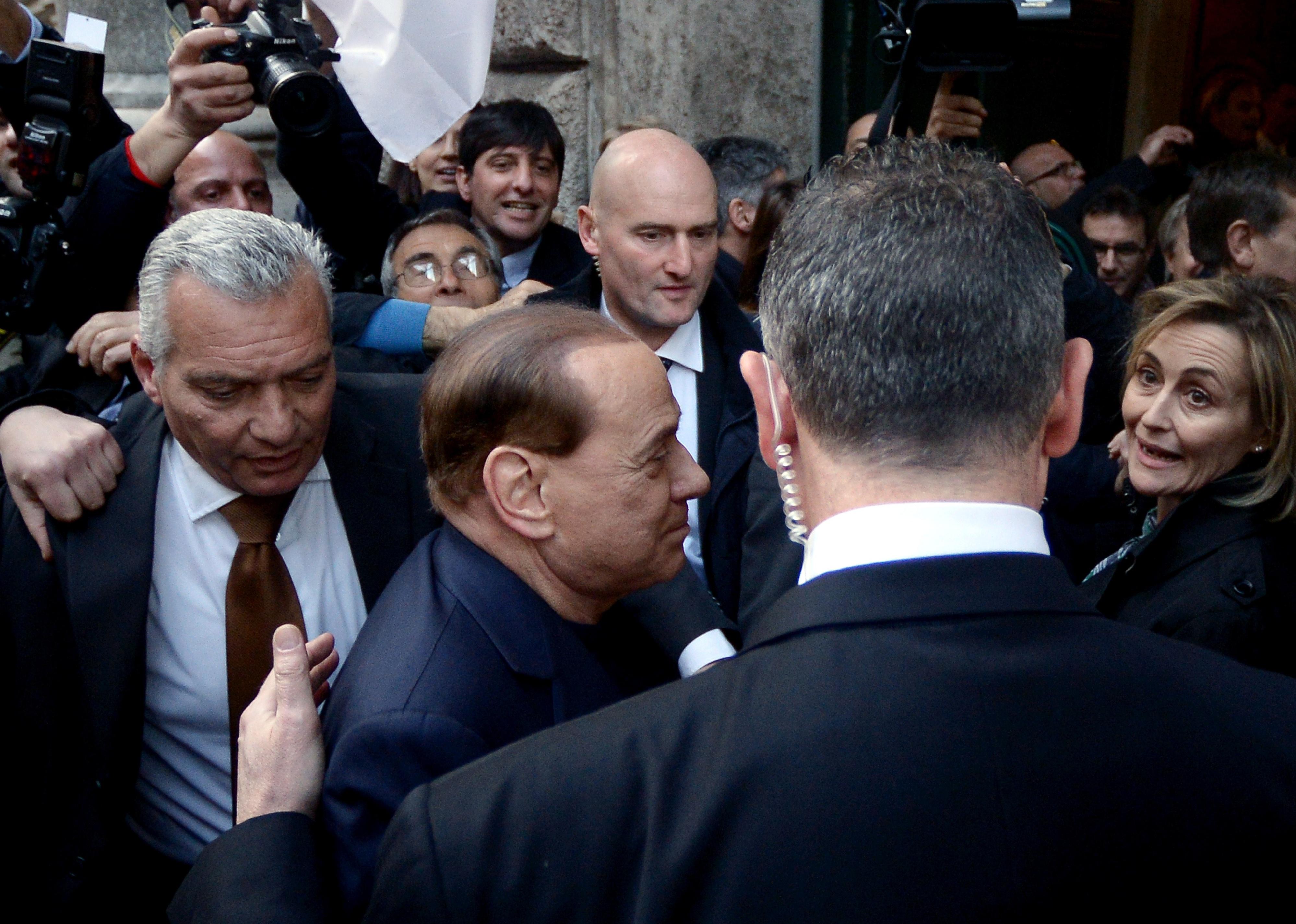 Silvio Berlusconi surrounded by bodyguards arrives at his home in downtown Rome