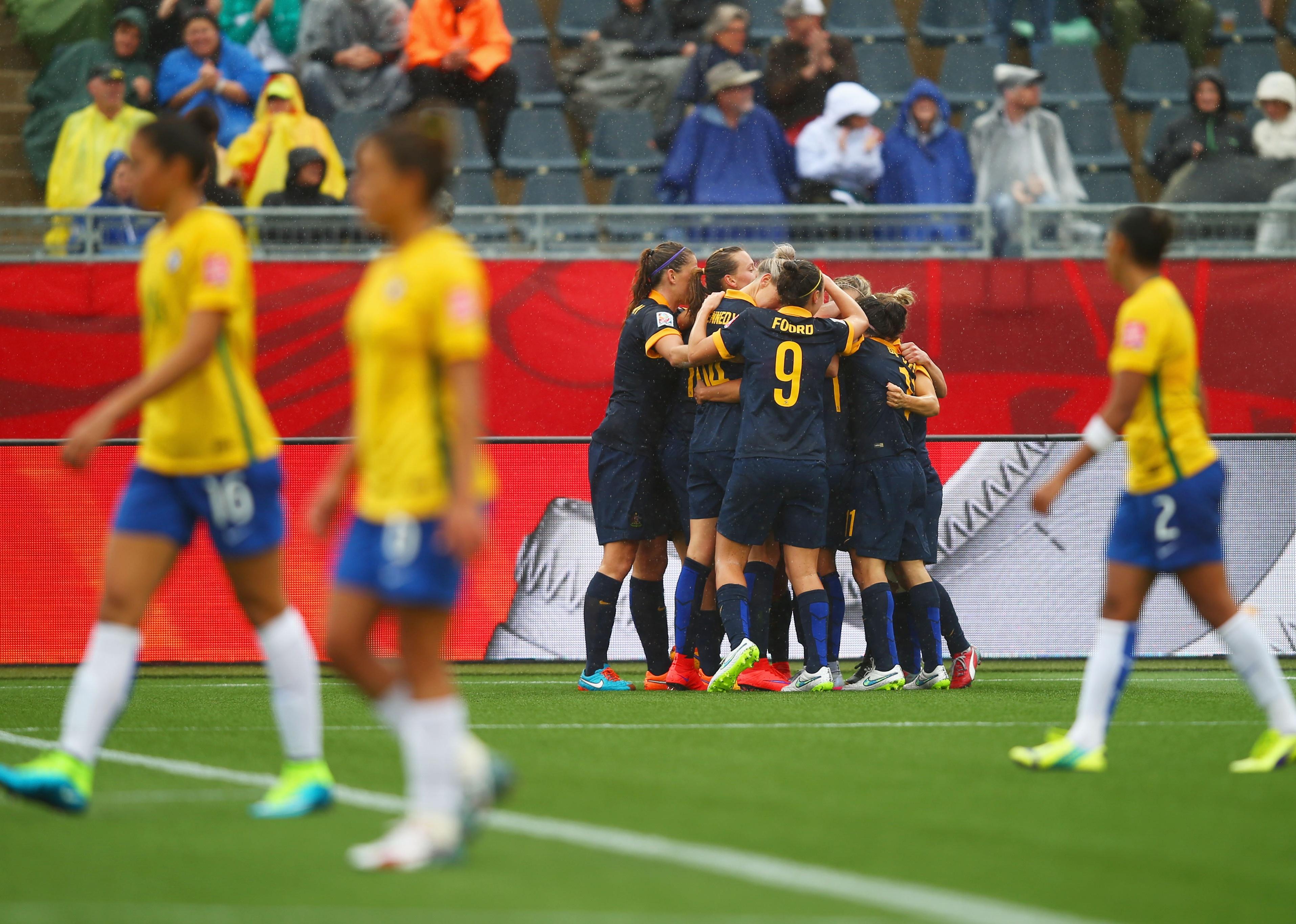 Brazil players look dejected as Kyah Simon of Australia celebrates with team after a goal.
