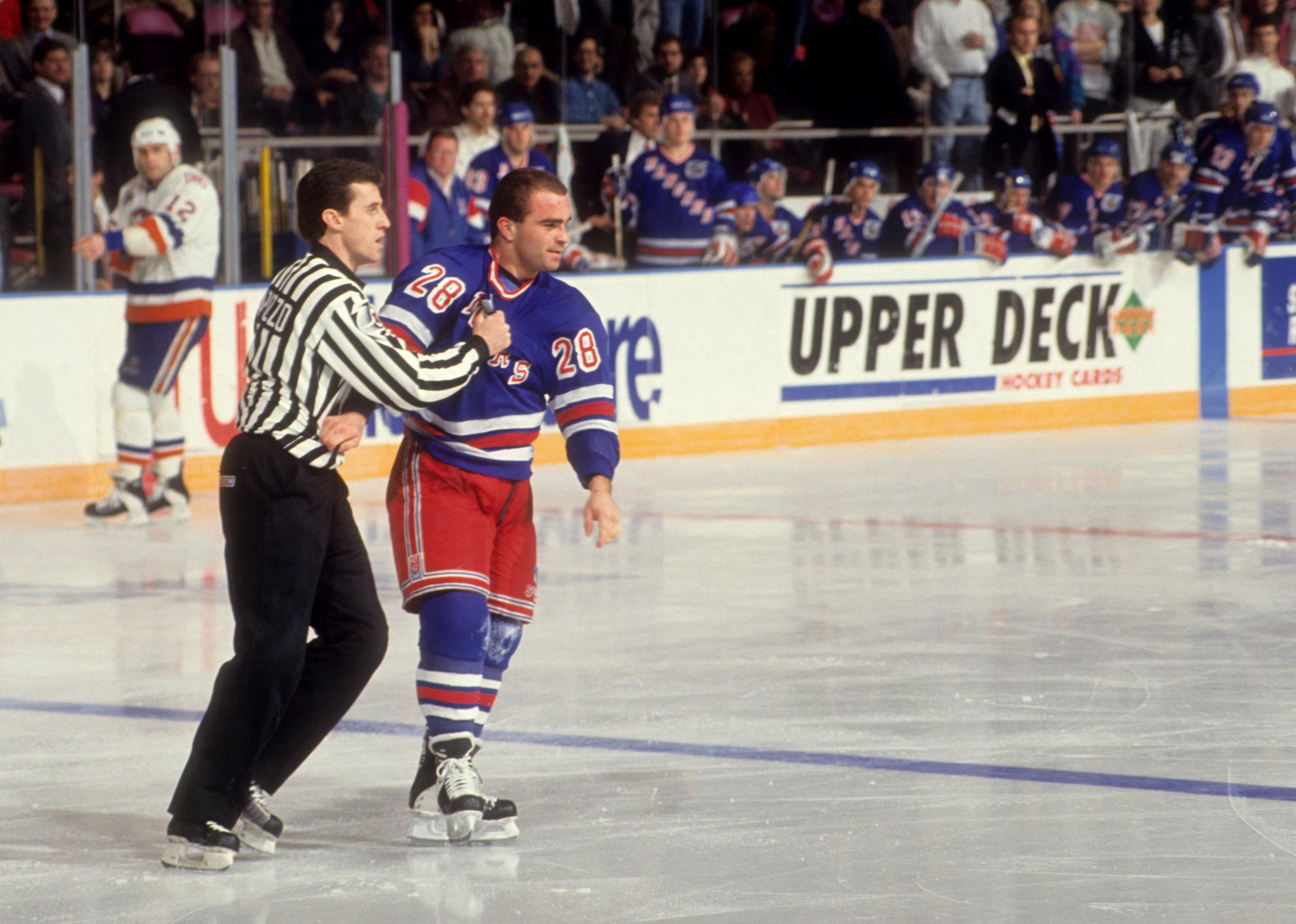 Tie Domi is held by a linesman after fighting during a game.