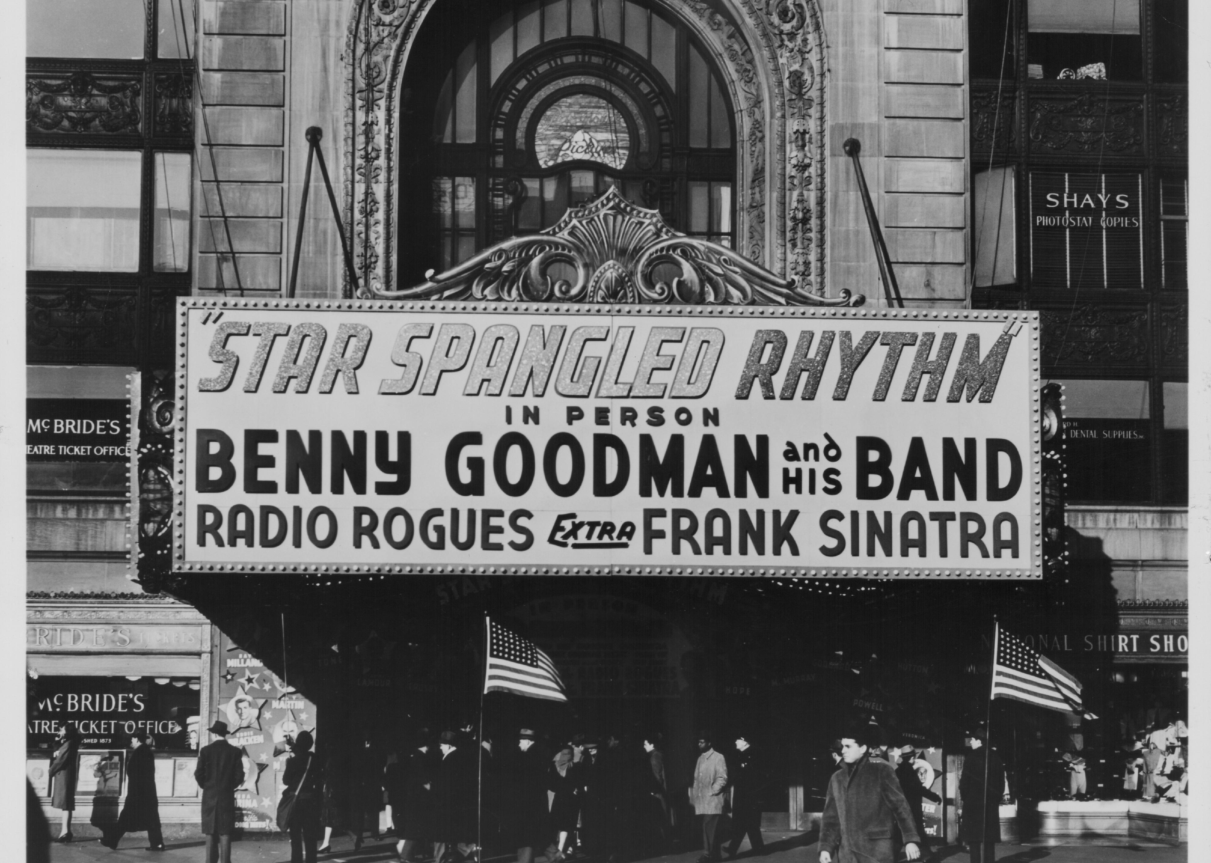 An advertisement awning outside a theater featuring Benny Goodman and Frank Sinatra.