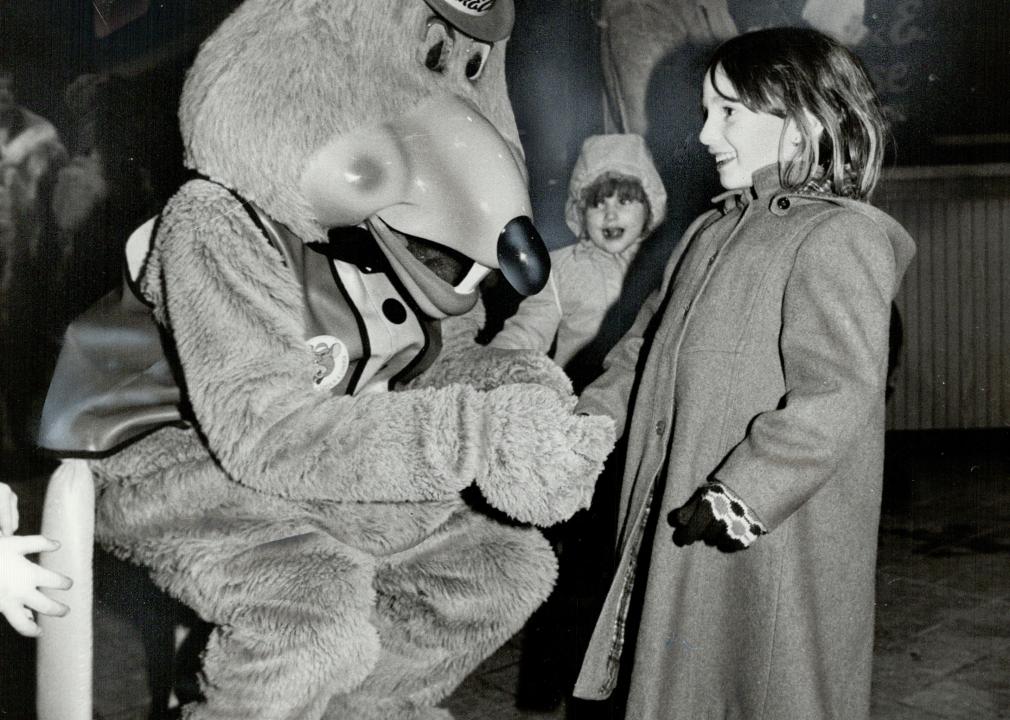 A young girl with a person dressed as Chuck E. Cheese in 1987.