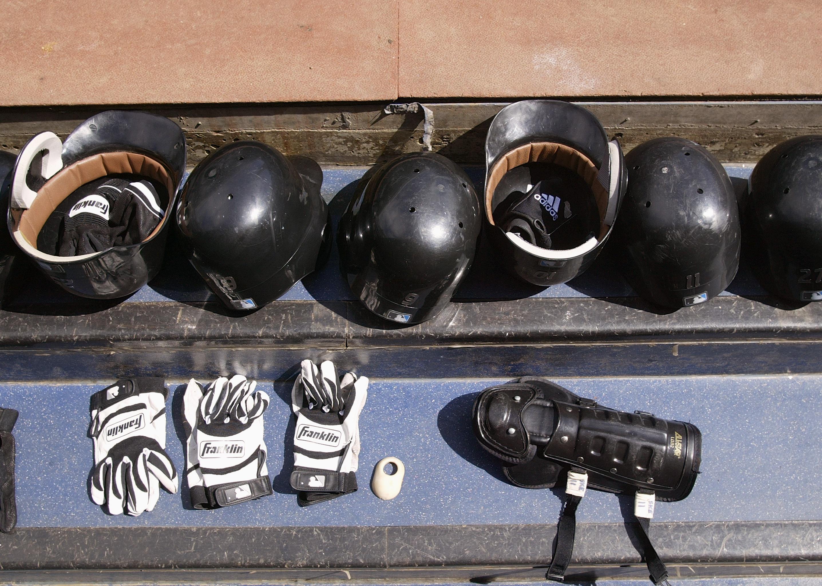 Detail of baseball helmets, gloves, and a knee guard.