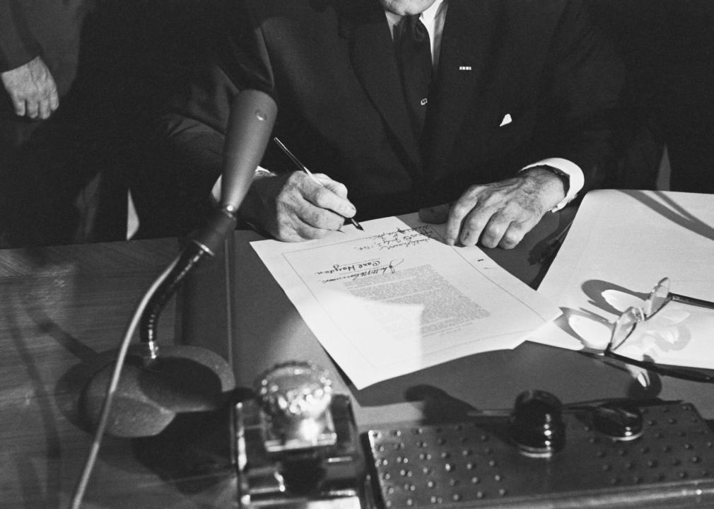 The hands of President Johnson rest on the signed Civil Rights bill 