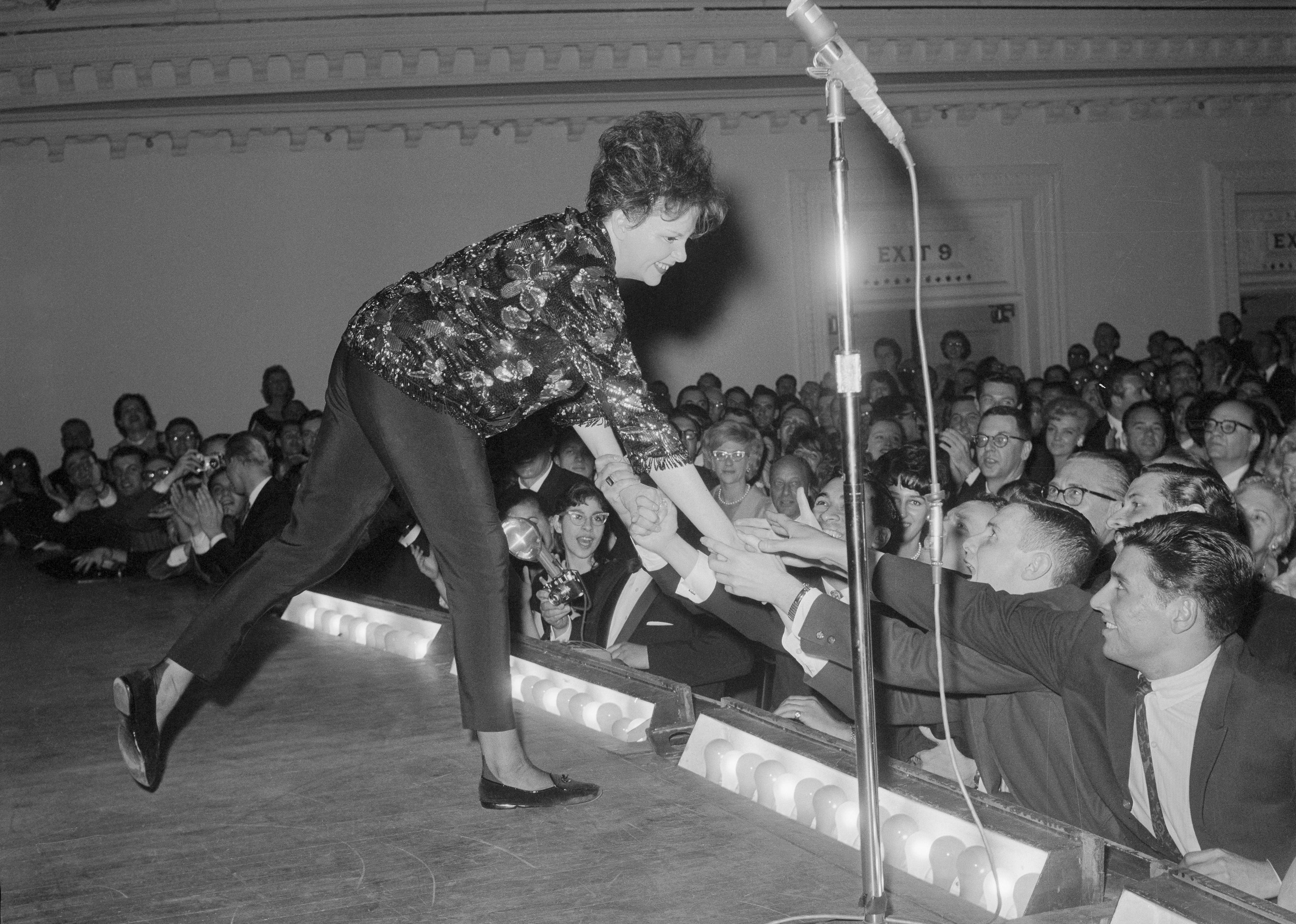 Judy Garland leans over the footlights to greet fans during a concert at Carnegie Hall. 