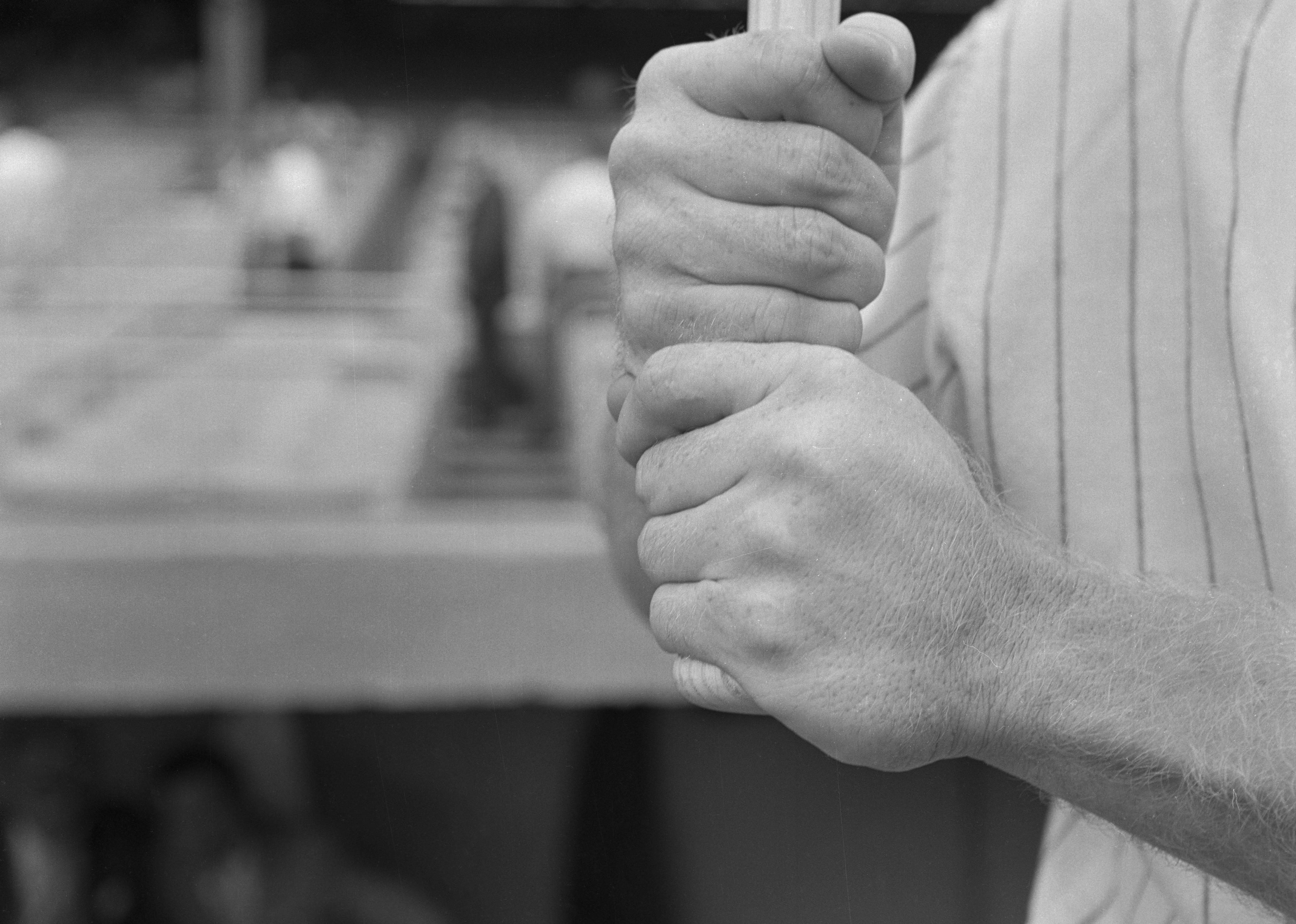 Black and white photo of a man gripping a baseball bat.