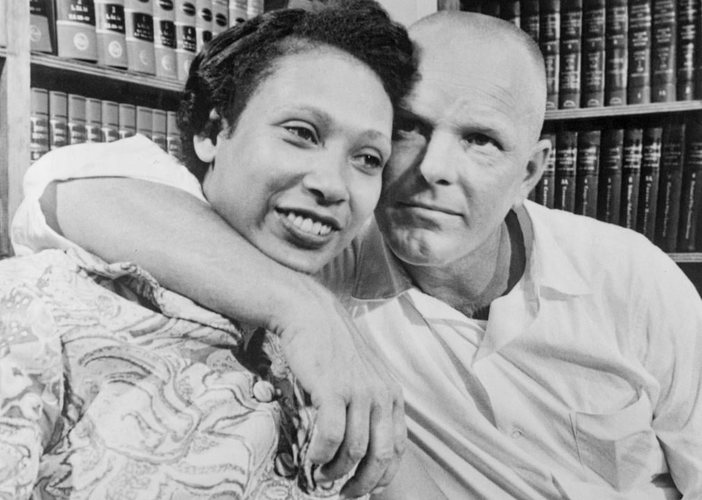 A well-known photo of Mildred Loving smiling next to her husband Richard who warmly has his arm around her.
