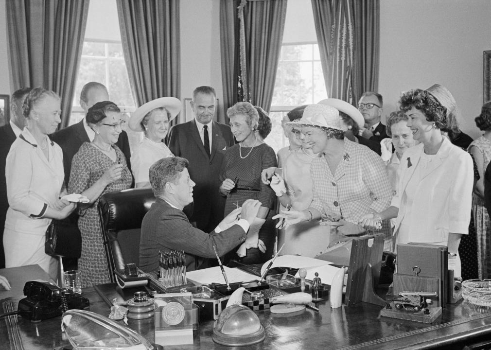 President Kennedy hands out pens during a ceremony 
