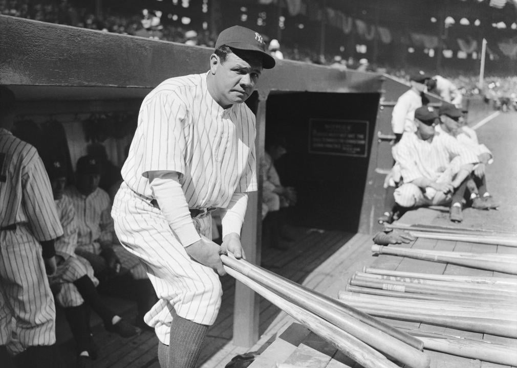 Babe Ruth lifting bats by a dugout