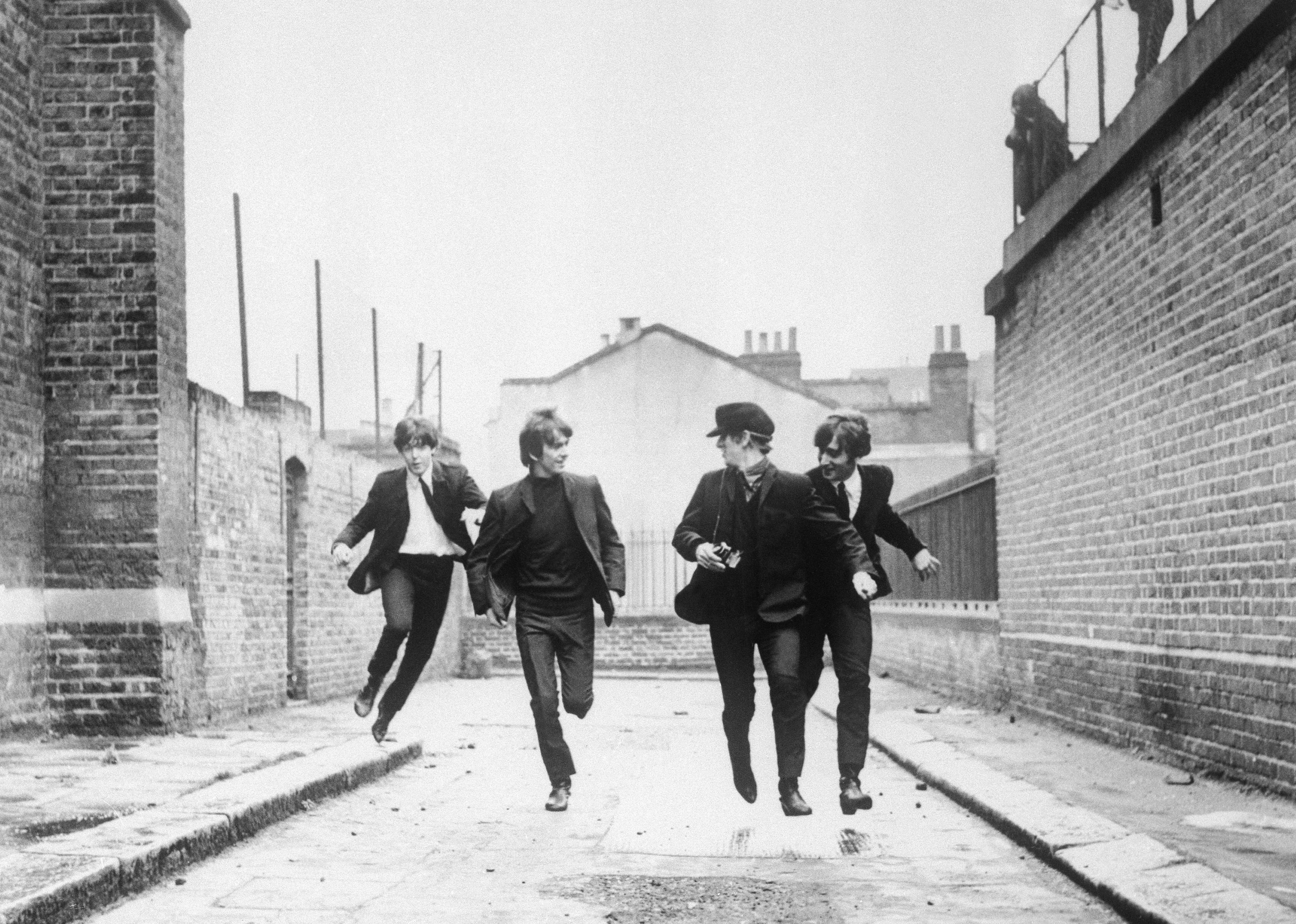The Beatles running down a street.