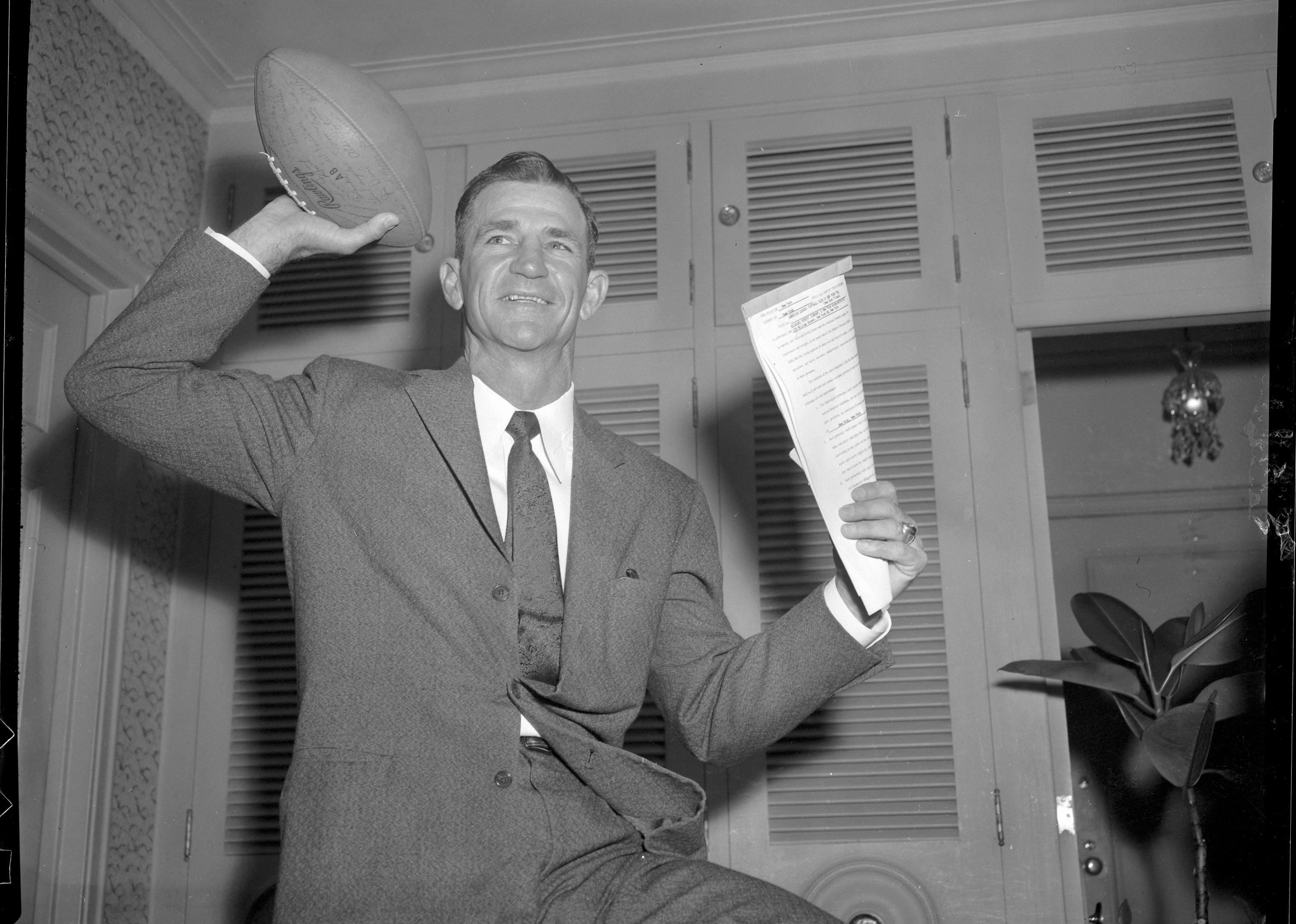 A contract and a football in hand, Sammy Baugh celebrates being named head coach of the New York Titans in the American Football League.