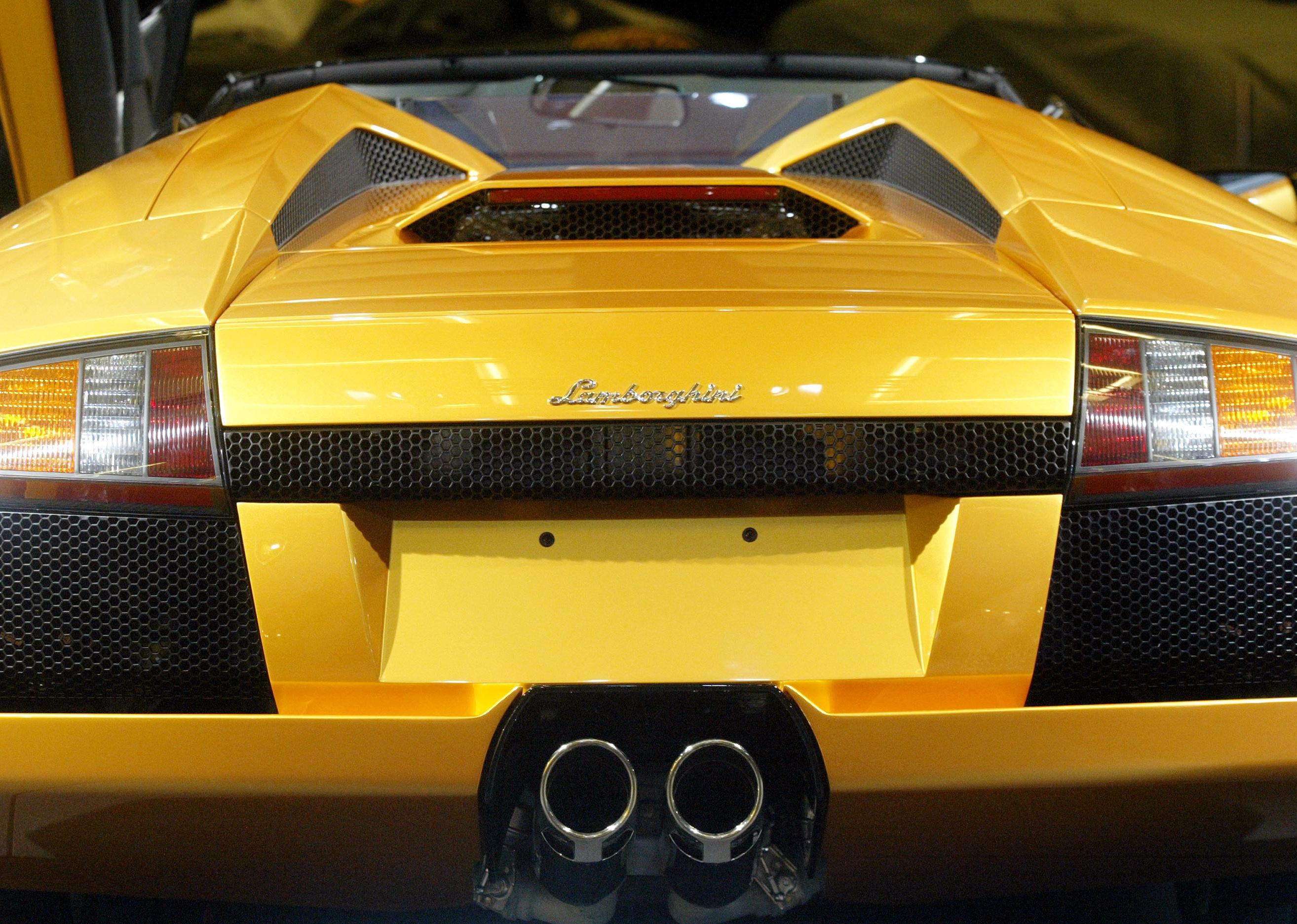 The Lamborghini Murcielago roadster stands on display with close up on logo.