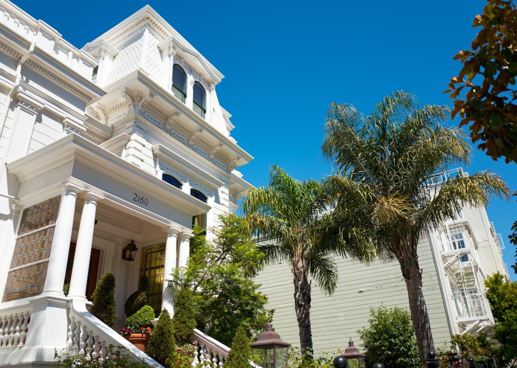 Elegant white Victorian-style mansion, with palm trees, on a sunny day in San Francisco.
