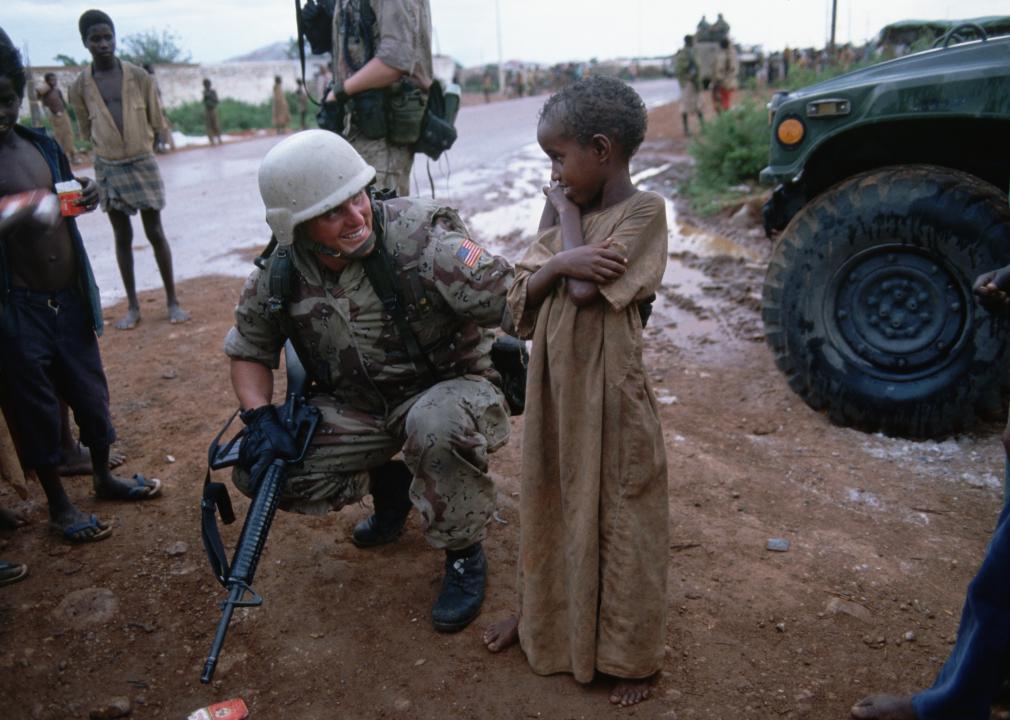 A solider stands with a Somalian child.
