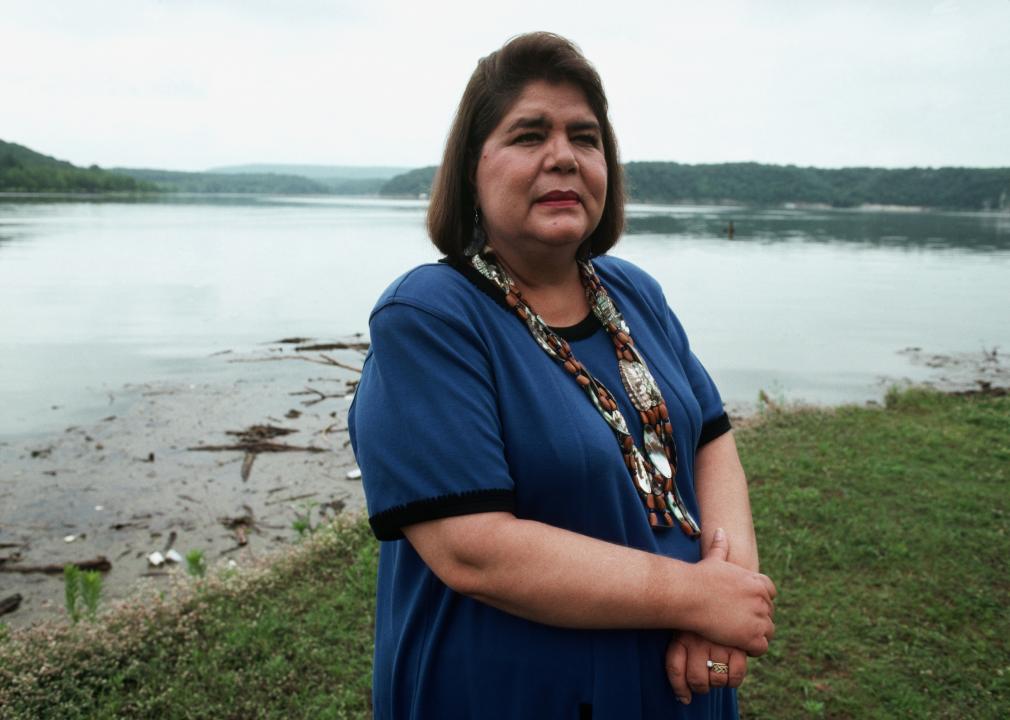 Wilma Mankiller poses outside near a lake. 