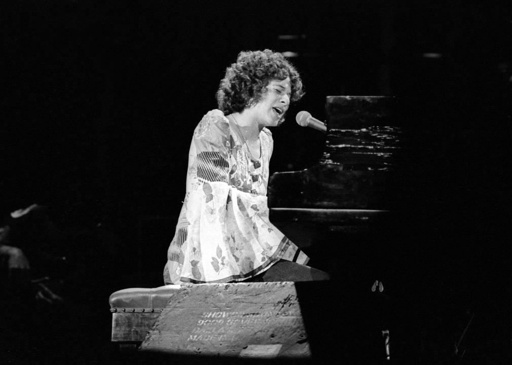 Carole King performing onstage at the piano.