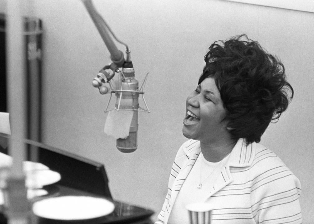 Aretha Franklin performing at piano in recording booth.