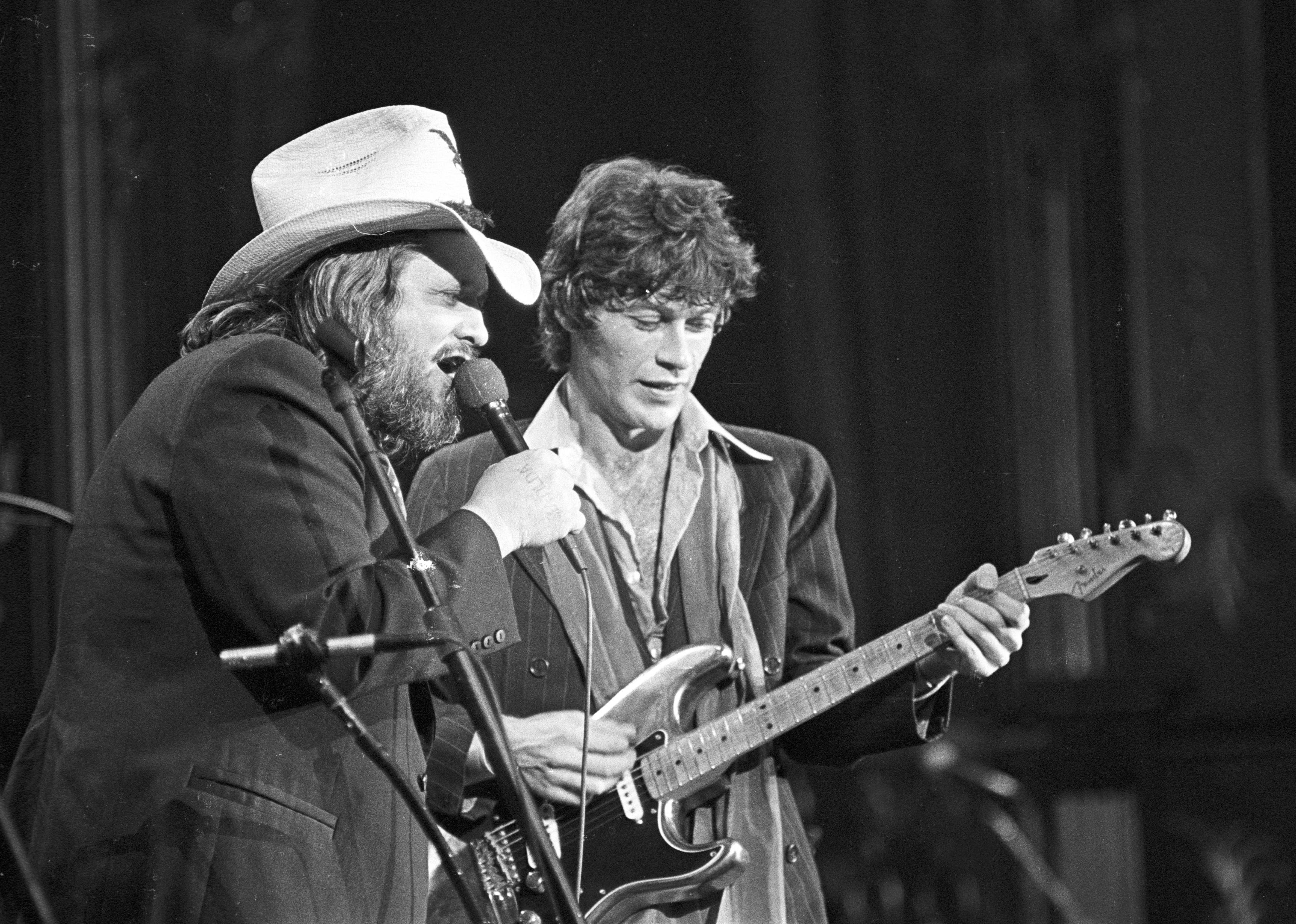 Musicians Ronnie Hawkins and Robbie Robertson perform on stage at The Band's 'The Last Waltz' concert.