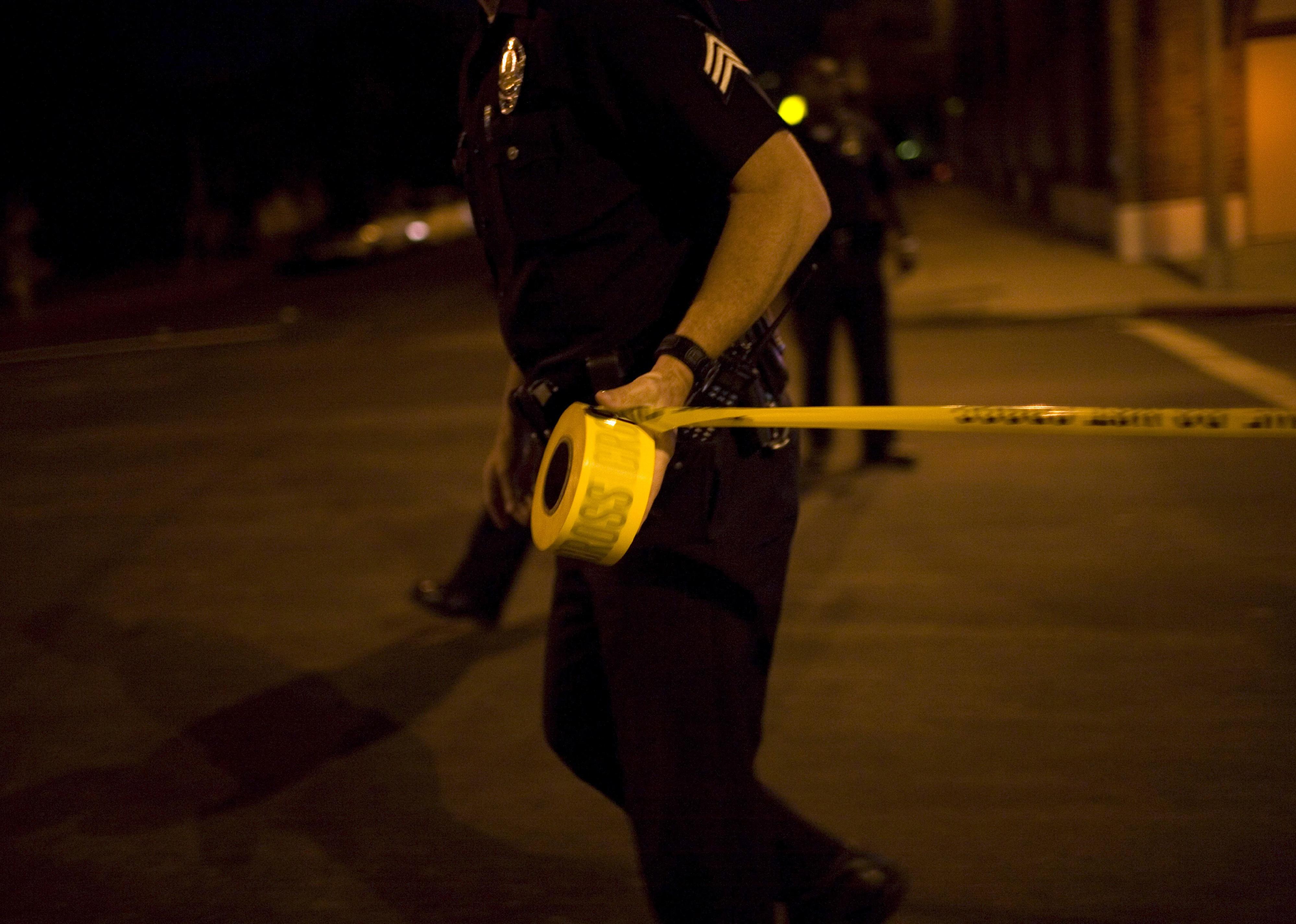 Los Angeles Police Department gang unit officers tape off a Crime Scene Investigation area.