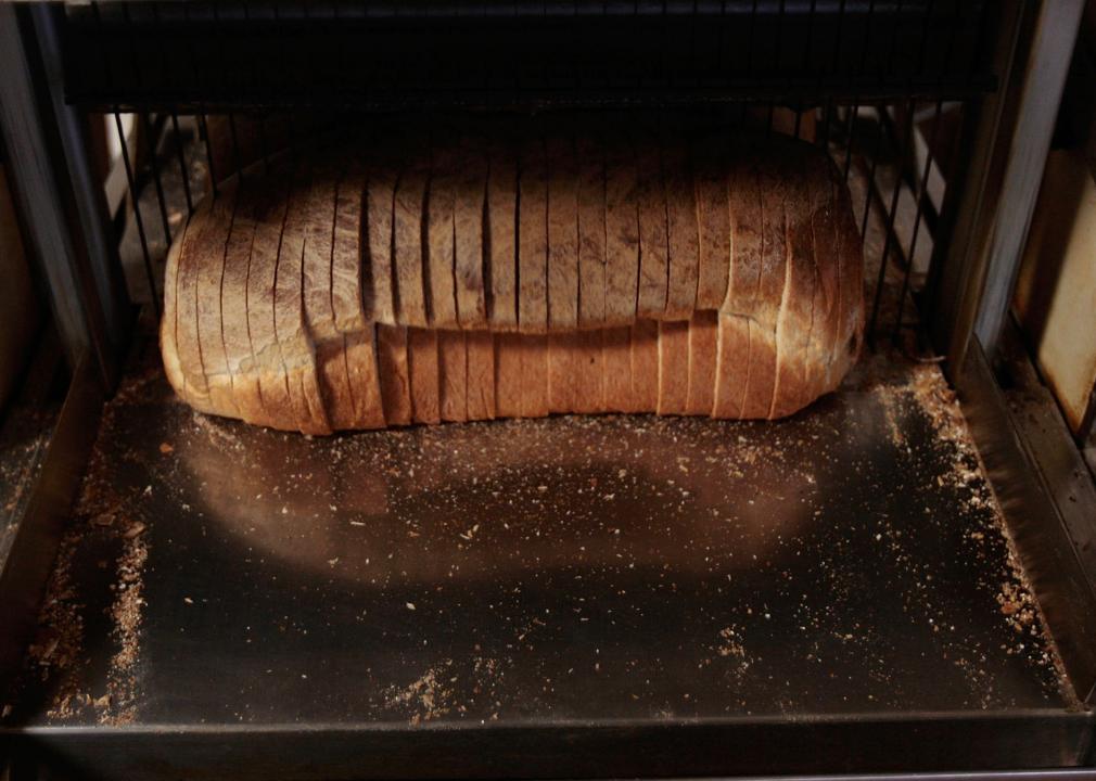 A loaf of bread moves through a bread slicer.