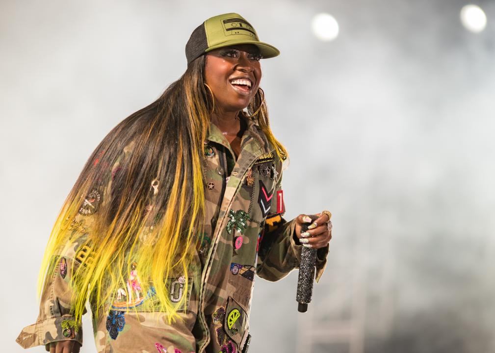 Missy Elliott performing onstage wearing decorated army fatigue outfit.