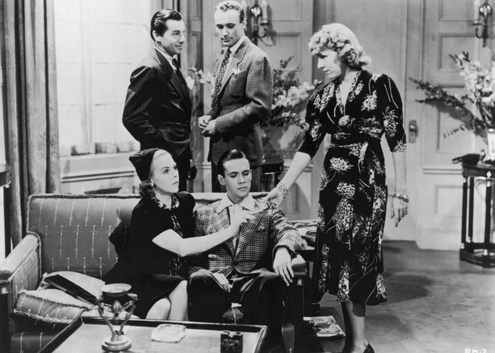 A still from Reefer Madness with five people in a living room passing a joint around.