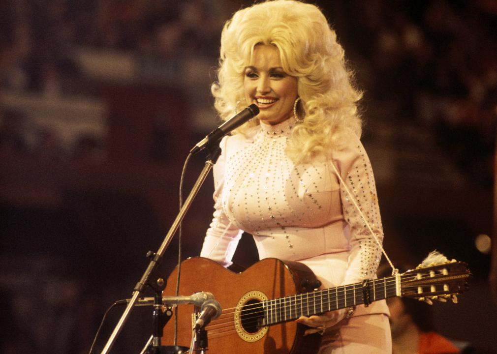 Dolly Parton, performs with a guitar, 1976. 