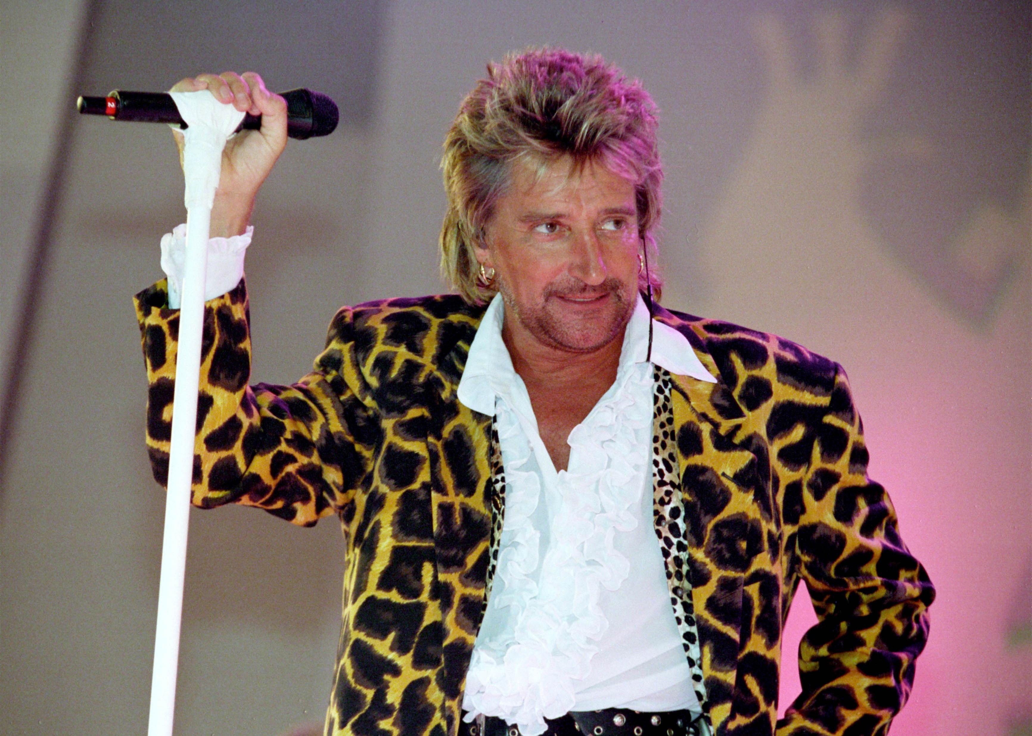 Photo of Rod Stewart performing live onstage, wearing leopard skin jacket.
