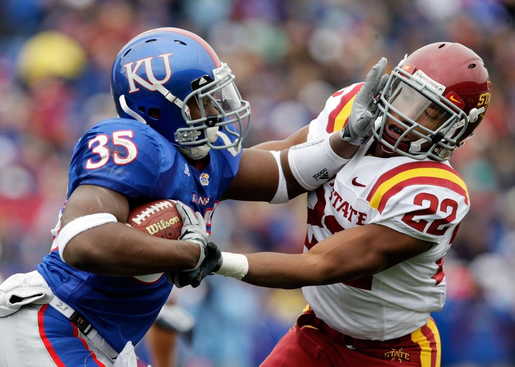 Running back Toben Opurum #35 of the Kansas Jayhawks stiffarms Ter'ran Benton #22 of the Iowa State Cyclones