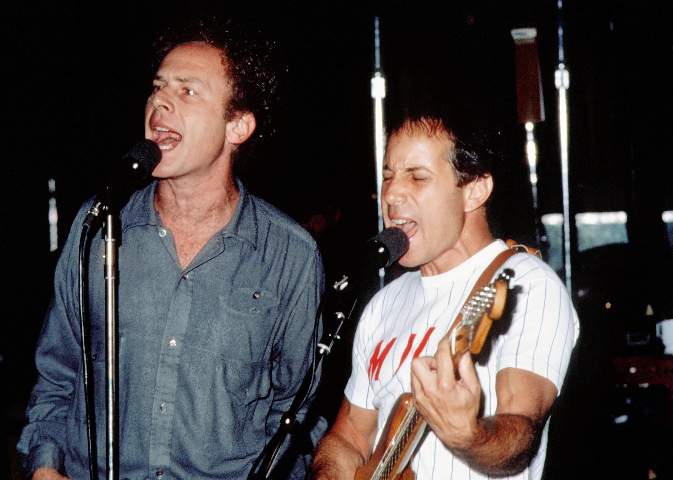 Paul Simon and Art Garfunkel performing onstage.