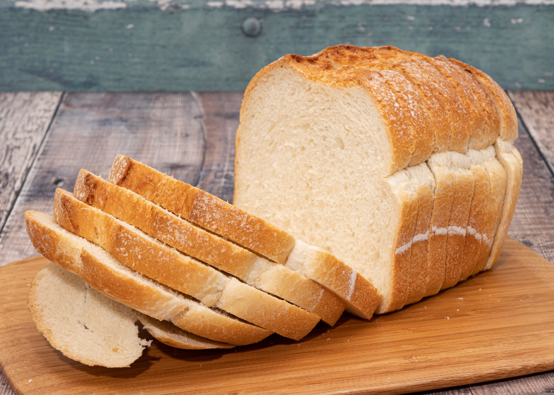 A loaf of sliced white bread on a cutting board.