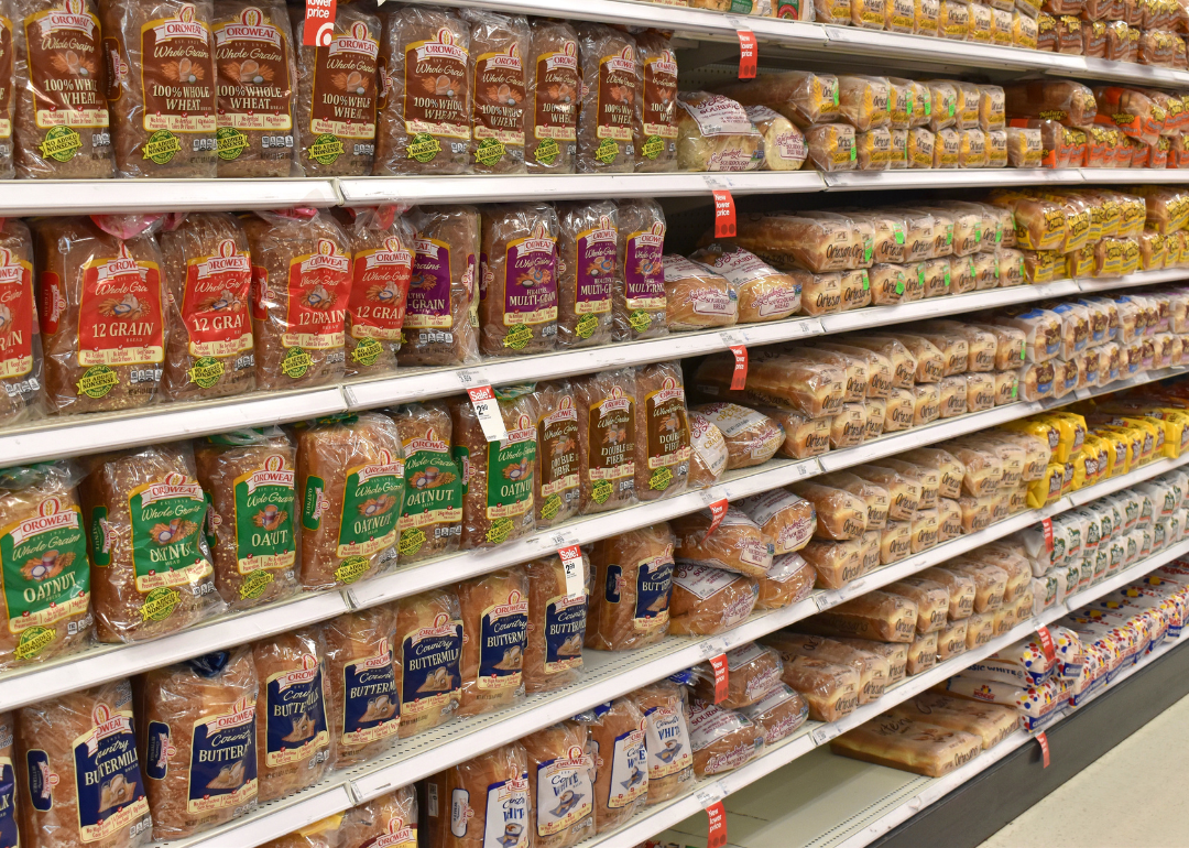 A grocery store shelf filled with various brands of bread.