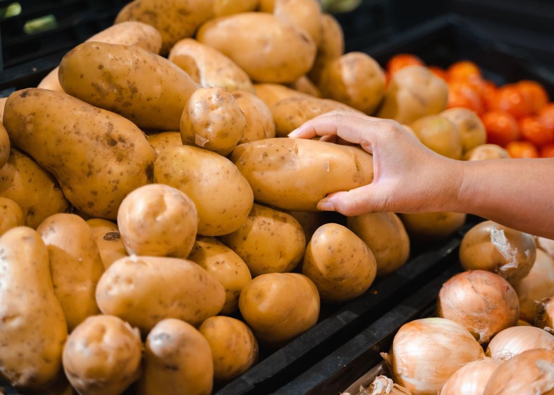 Person picking up potato in supermarket