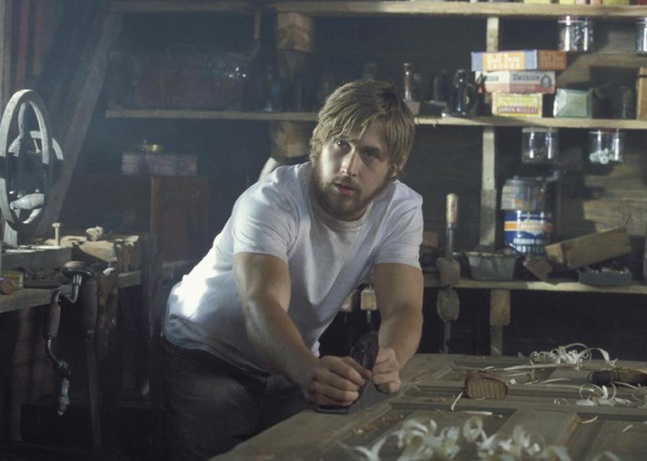 Ryan Gosling sanding down a door in a workshop.