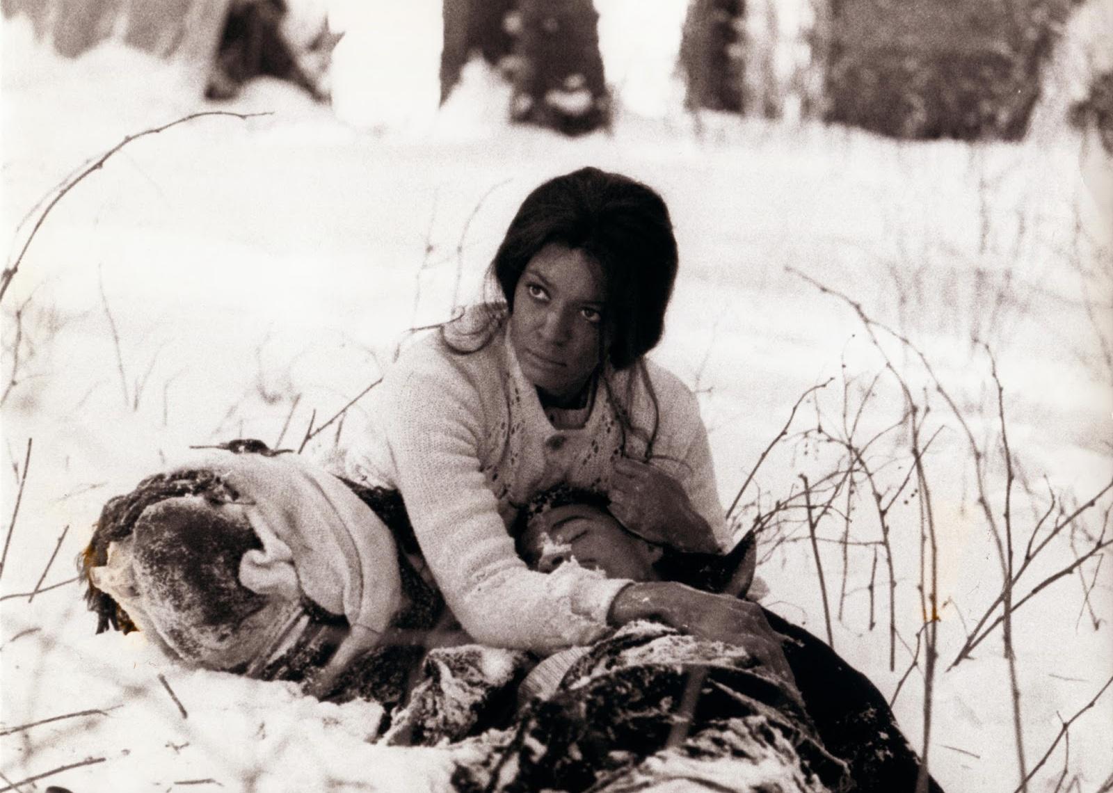 A woman clings to a man lying in the snow.