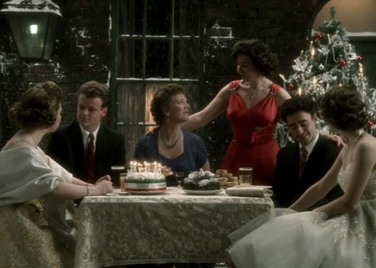 A dressed up family sitting at a dinner table in front of a Christmas tree.