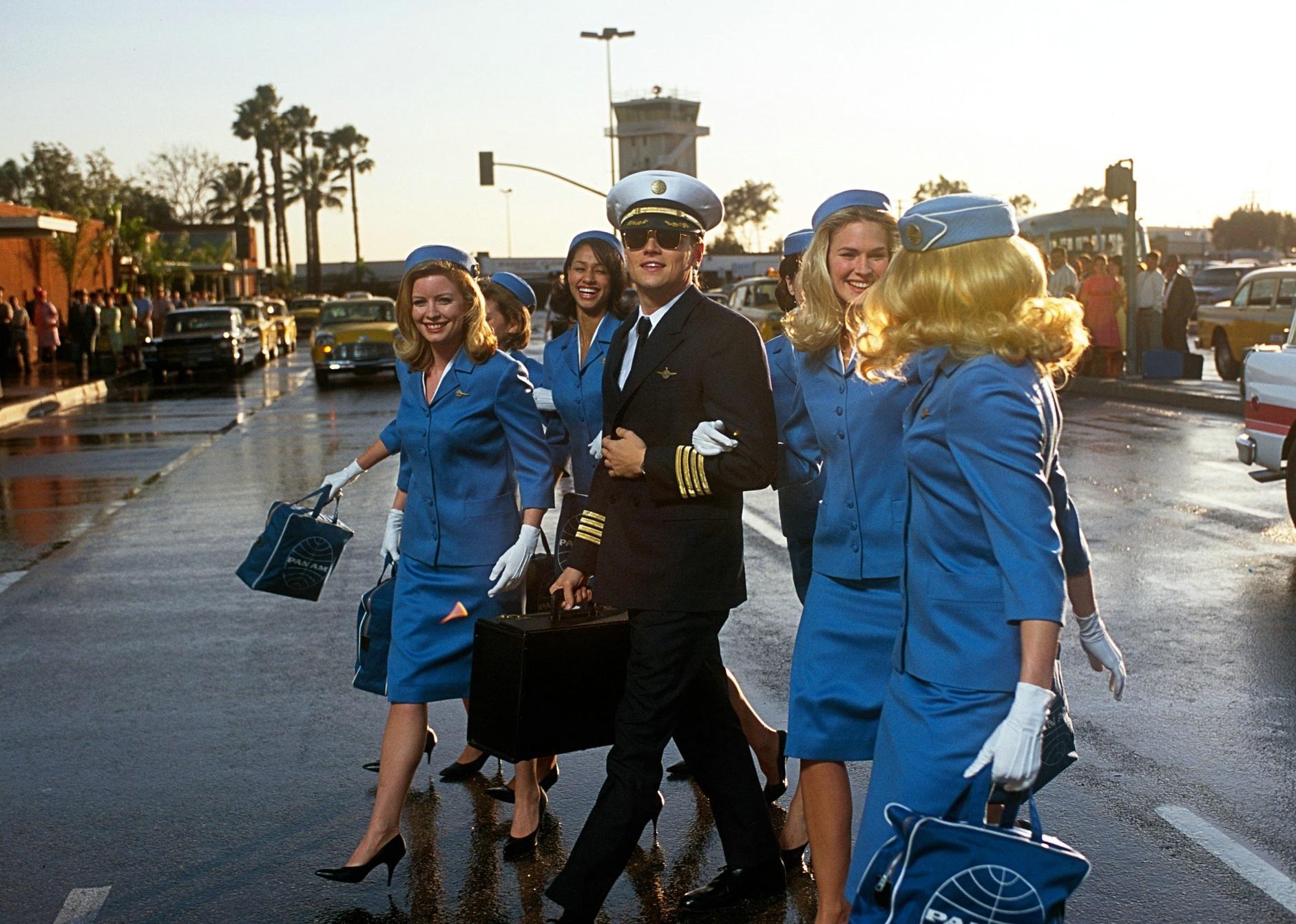 Leonardo DiCaprio walking with a group of female flight attendants.
