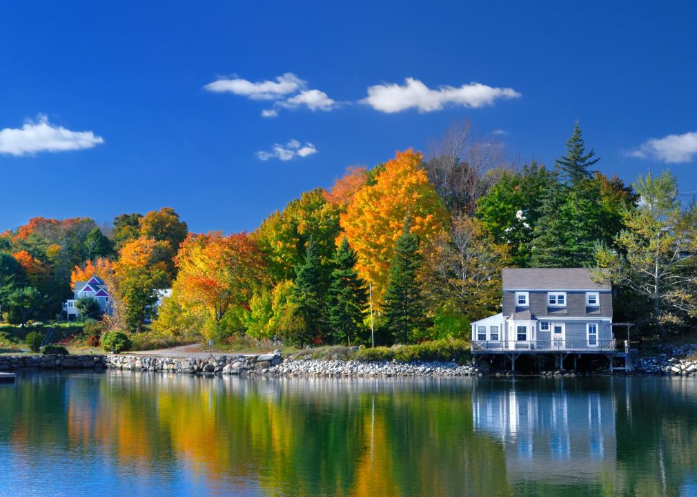 Sparse homes on the water surrounded by colorful foliage.