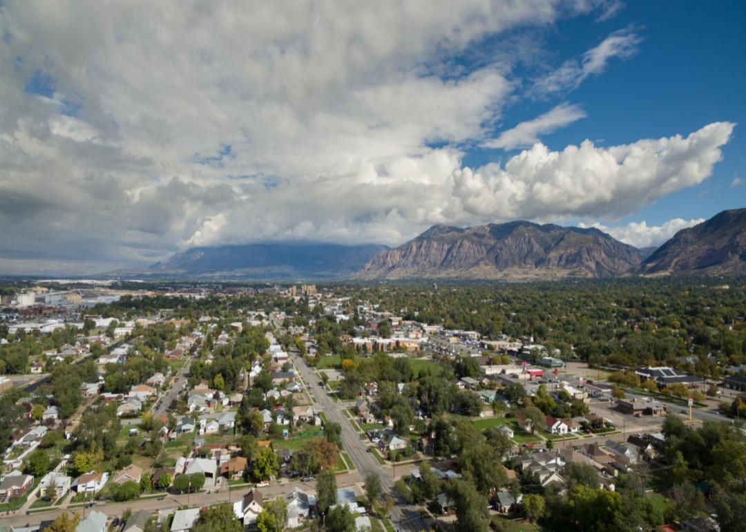 An aerial drone view high above Ogden, Utah, looking towards downtown and the commercial district with a beautiful sky, clouds and mountains in the background.