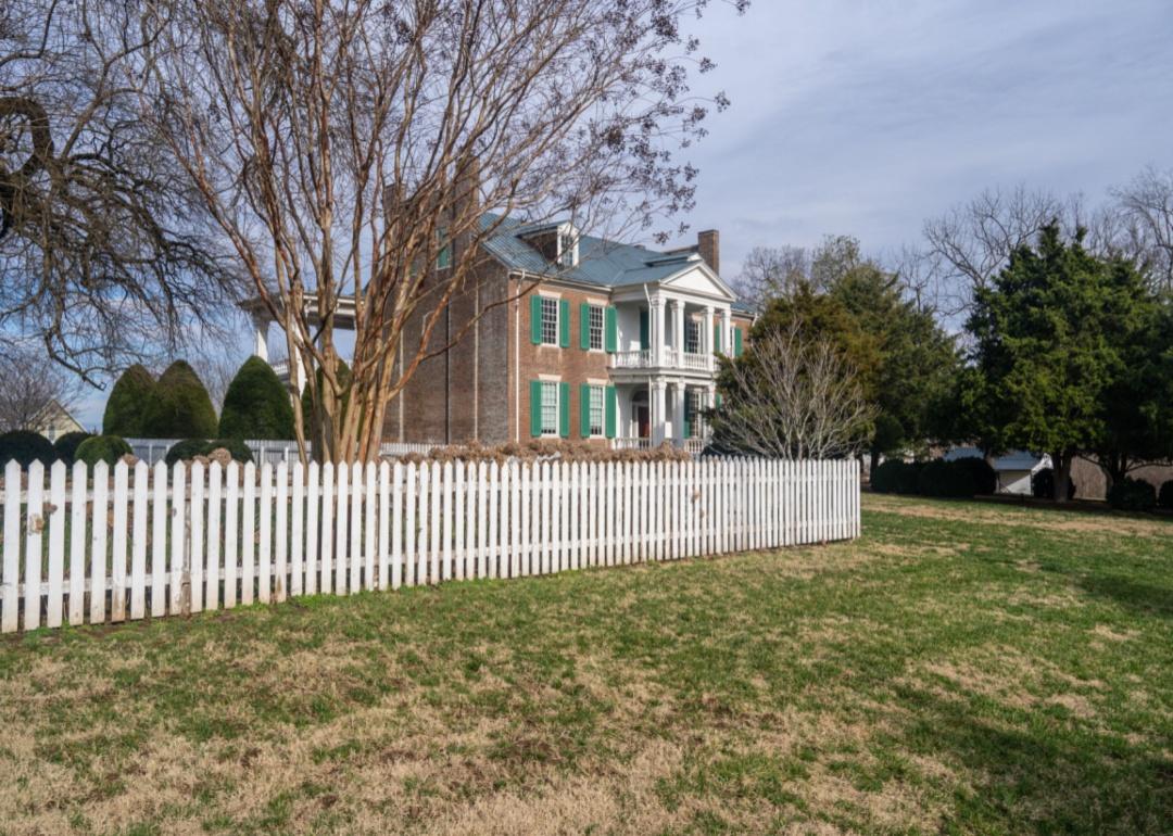 A historic home with green shutters and a white picket fence.