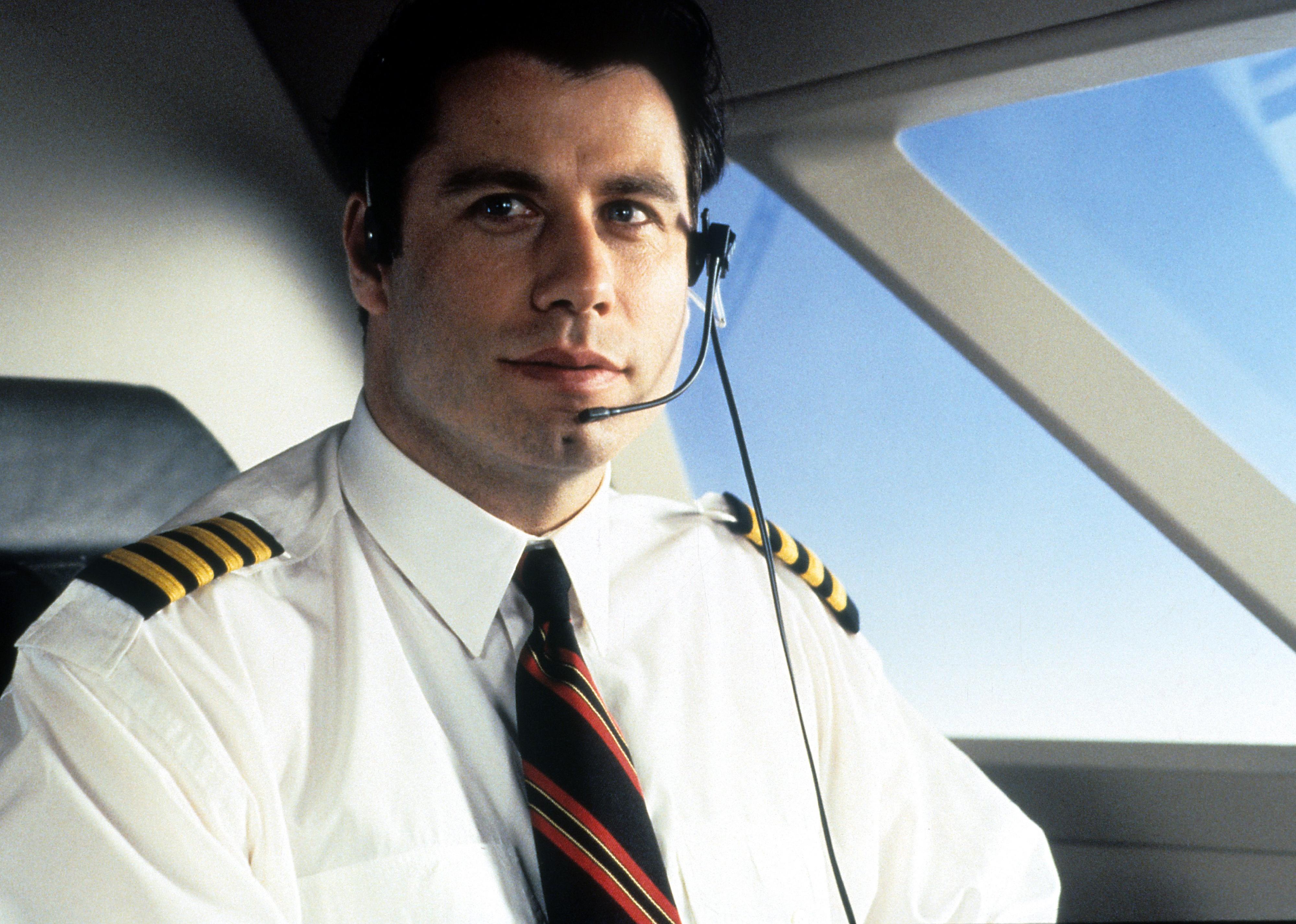 John Travolta dressed as a pilot flying an airplane.