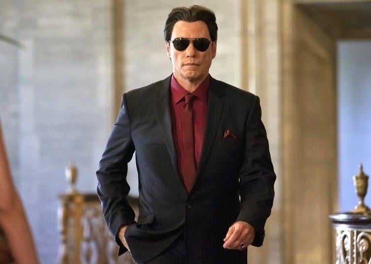 John Travolta in a black suit and dark sunglasses.