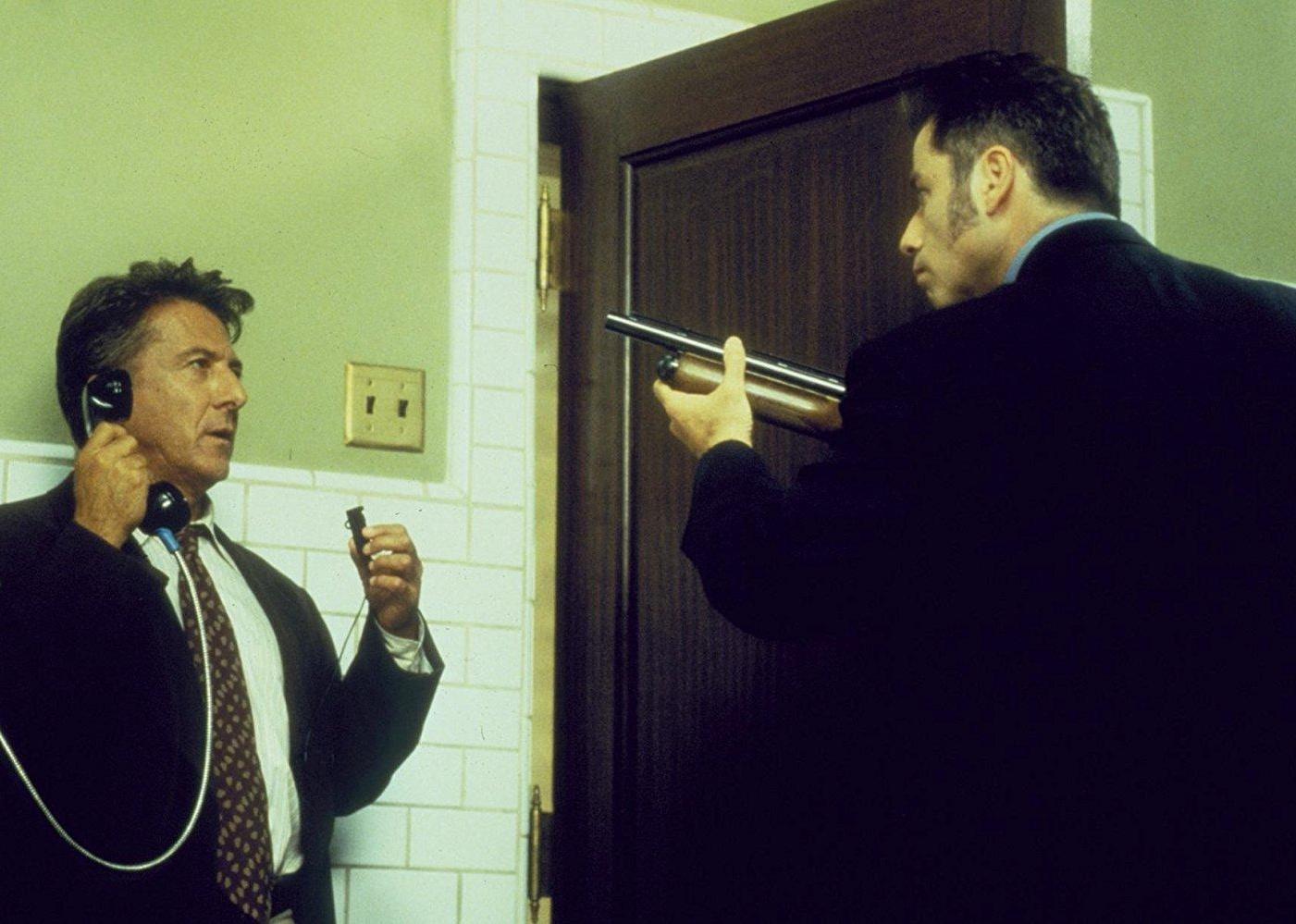 John Travolta holding a long gun up to Dustin Hoffman, who is on the phone.